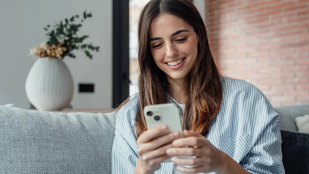 En person som holder en mobiltelefon på sengen
